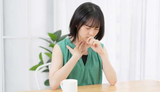 喉を押さえる女性